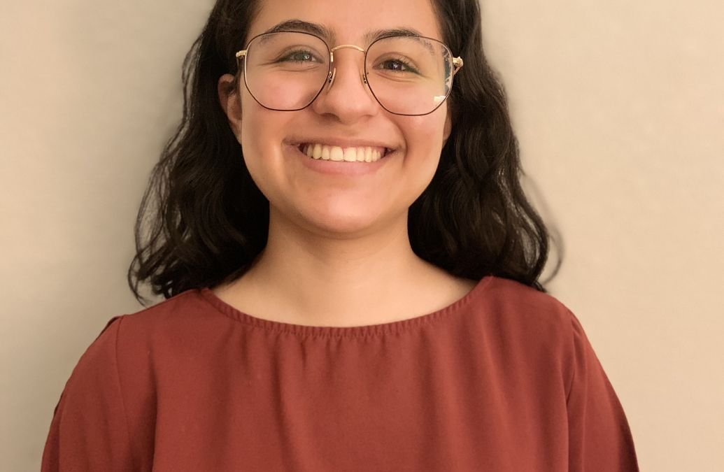 head and shoulders portrait of smiling young woman in glasses with dark hair and red shirt