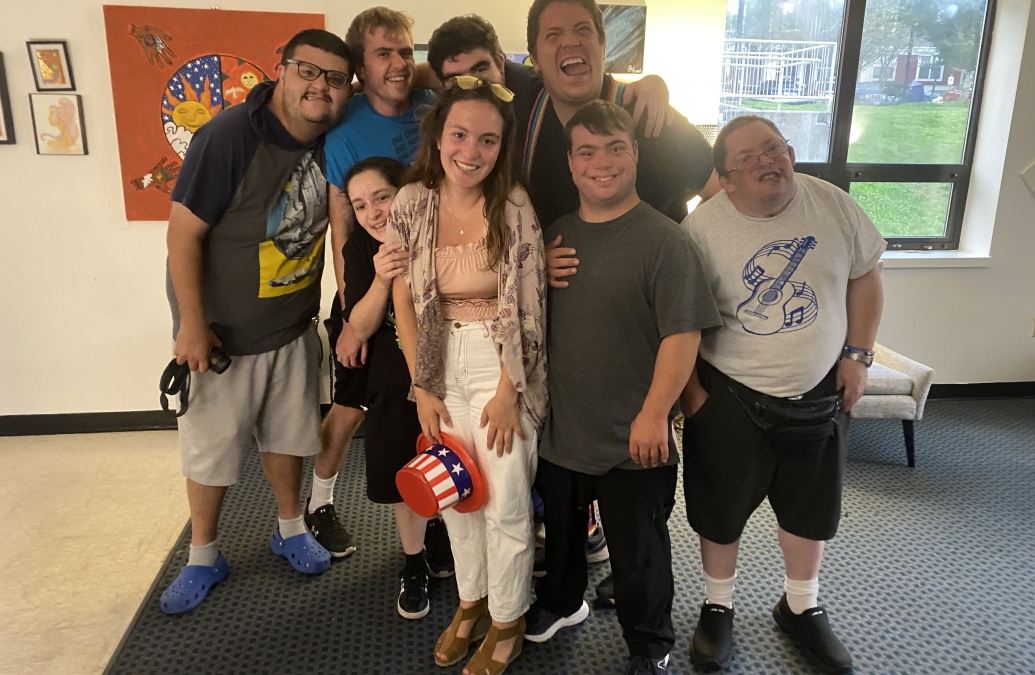 group portrait of young students smiling surrounding a young woman