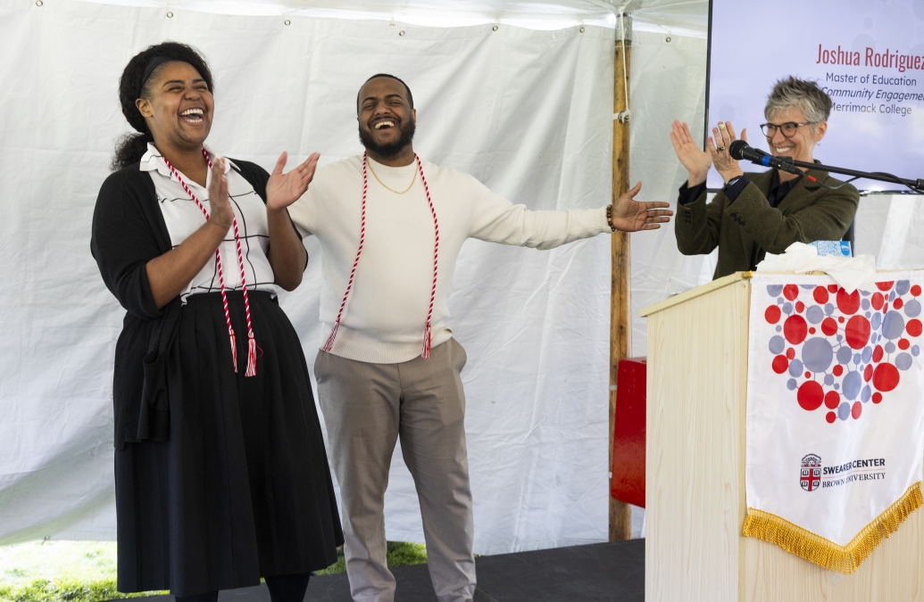 three adults laughing on stage behind a podium during an awards ceremony