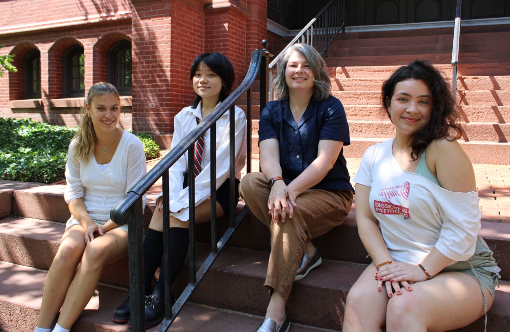 four adults sitting outside on a stone staircase with iron railing