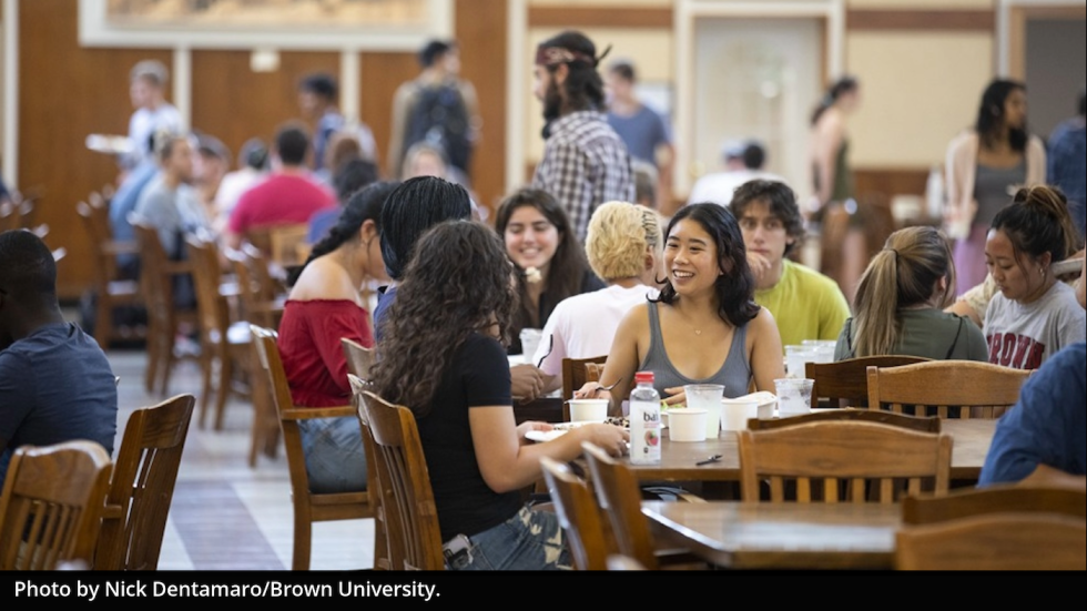 Students sitting, smiling and eating together at a table.