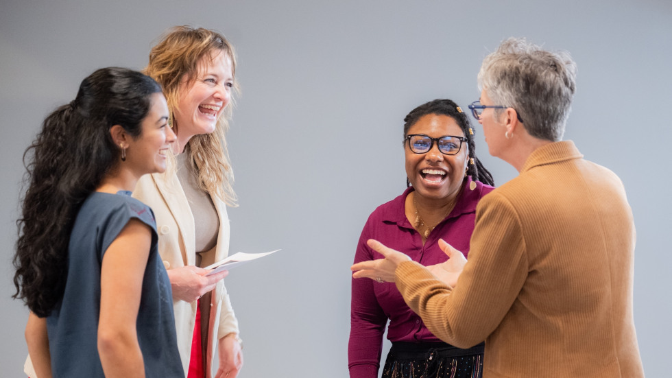 Four attendees stand together smiling, laughing and talking during the Royce Fellowship 30th Anniversary Celebration.